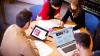 A group of students using a laptop, a tablet and books to prepare for an IELTS exam