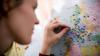A woman fixing pins to different locations on a world map